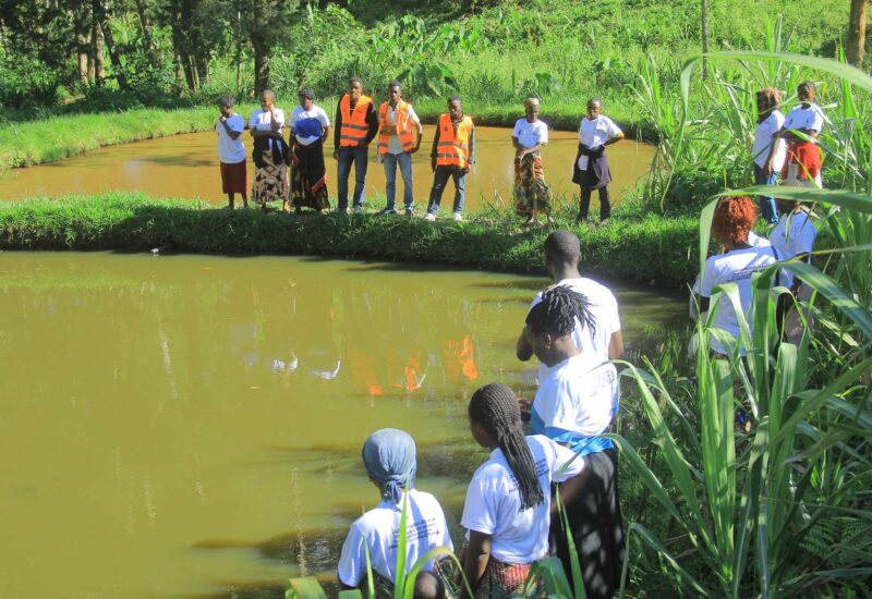Groupe de jeunes femmes réunies autour d'un étang piscicole communautaire